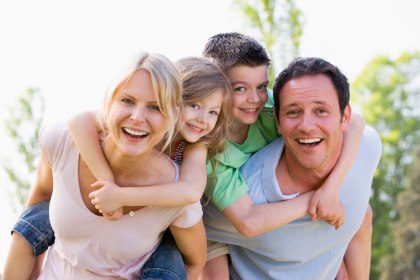 Eltern tragen zwei Kinder huckepack, lachend, © istockphoto.com©monkeybusinessimages